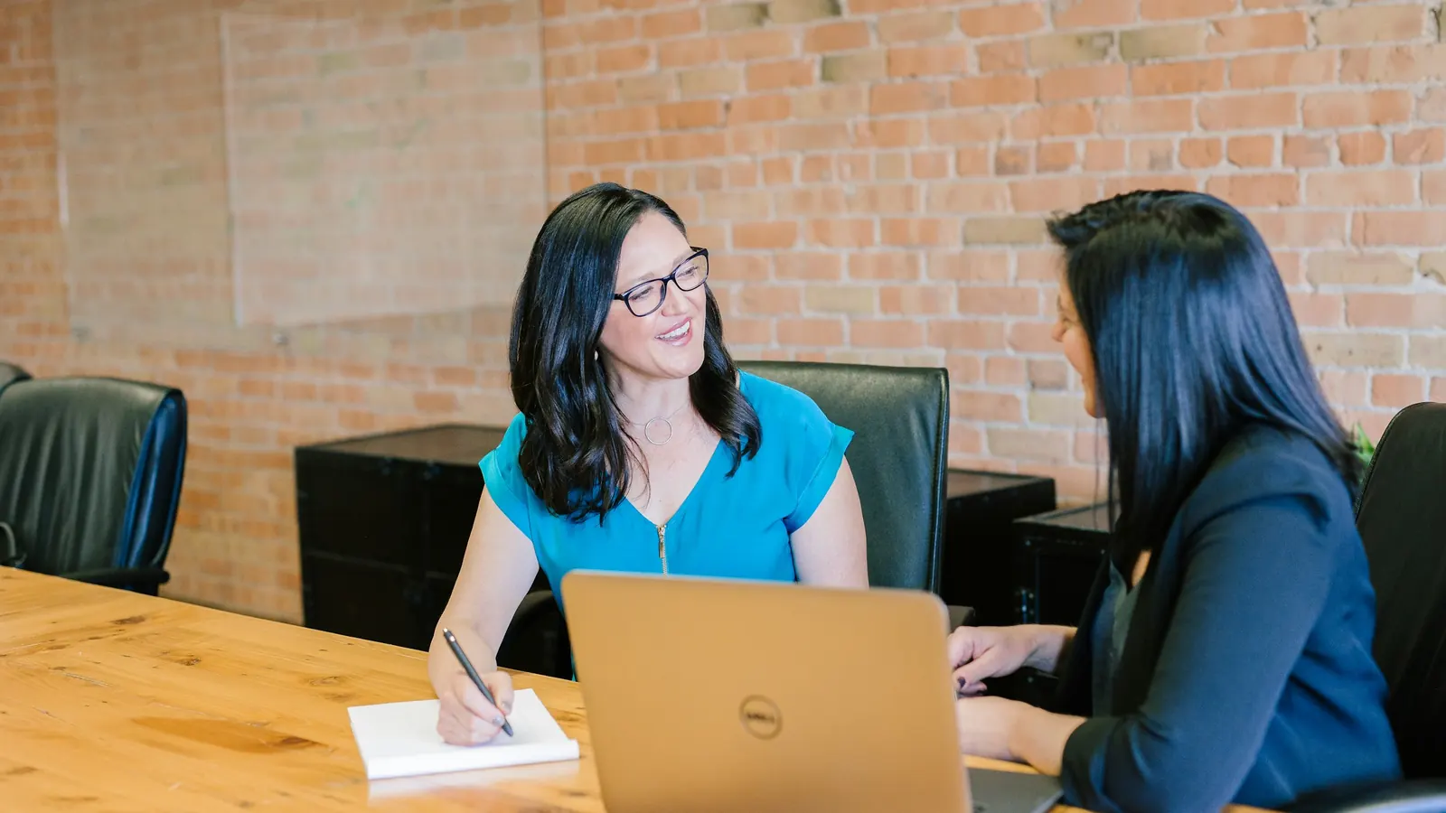 Two professionals planning employee relocation housing on a laptop