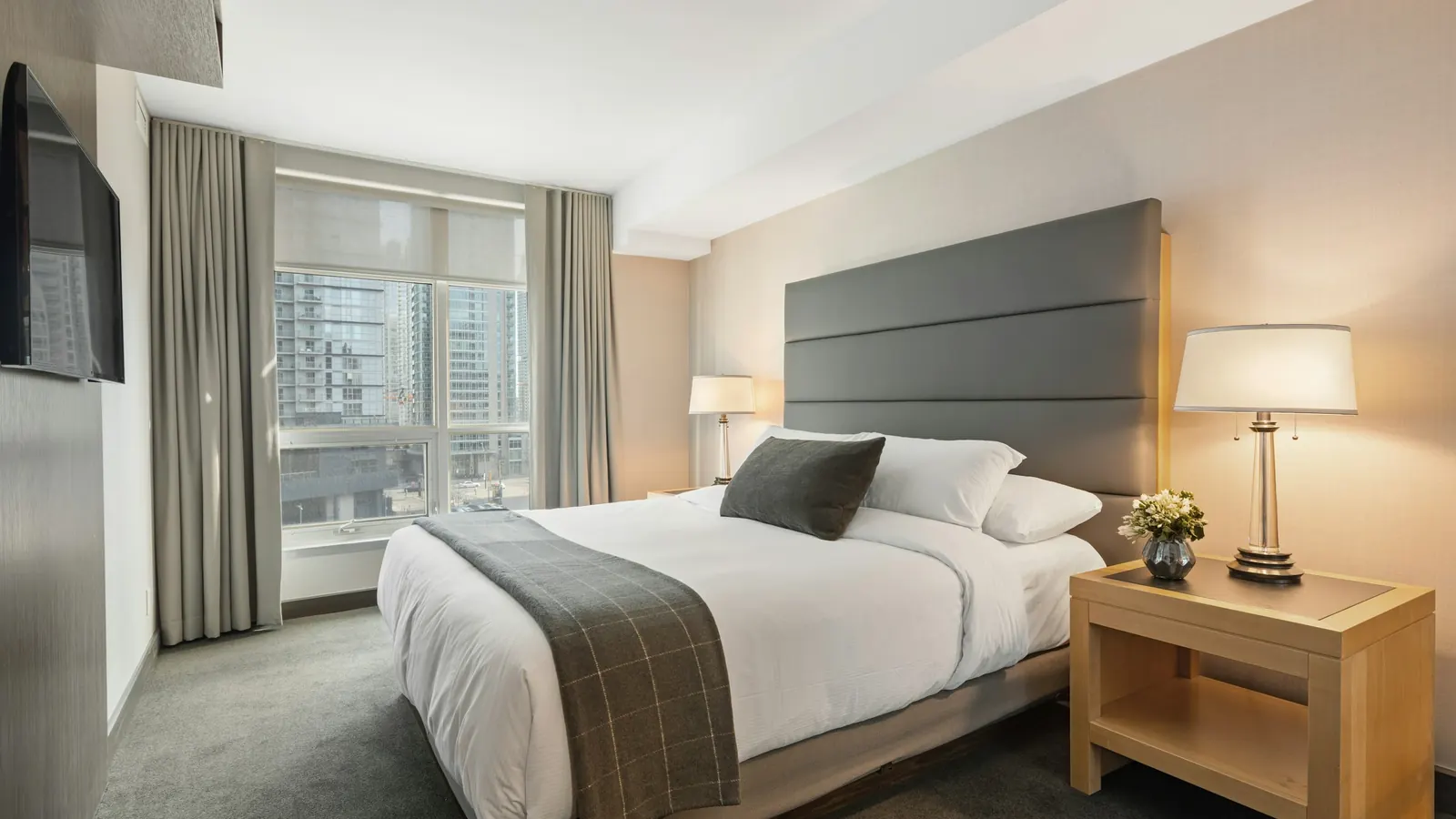 Standard hotel room with a bed and nightstand, compared with corporate housing for extended business stays